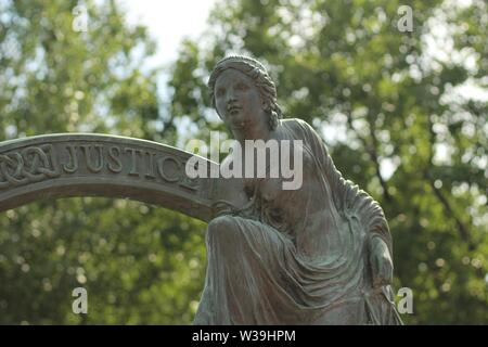Nahaufnahme einer weiblichen Statue an einem sonnigen Tag mit Unscharfe Bäume im Hintergrund Stockfoto