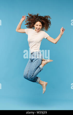 Junge freudige brünette Frau in weißem T-Shirt und Blue Jeans zum Ausdruck Aufregung beim Springen in der Isolation Stockfoto