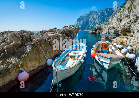 Hell gestrichenen Wassertaxis mit bunten Zubehör angedockt in einer felsigen Bucht im Mittelmeer auf der Insel Capri, Italien Stockfoto