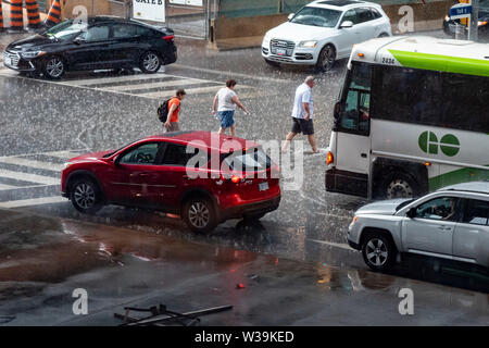 Toronto, Kanada. Juli 13, 2019. Schwere Nachmittag Regen hat viele Kreuzungen in der Innenstadt von Toronto überflutet. Bild Fußgänger Lauffläche durch Wasser während der Überfahrt an York und See. Credit: EXImages/Alamy leben Nachrichten Stockfoto