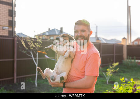 Menschen, Haustiere und Hunde Konzept - junge Mann umarmen funny Jack Russell Terrier im Freien Stockfoto