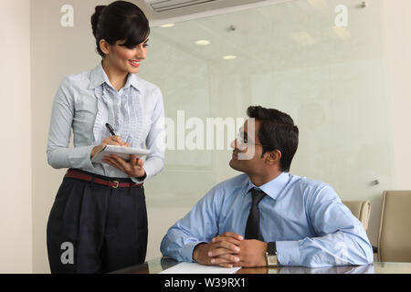 Geschäftsmann diktiert Notizen an Sekretär Stockfoto