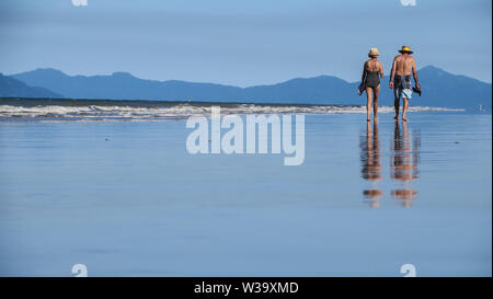 Das Leben ist ein Strand in Australien vor allem auch sehr gut für ältere Menschen, in den Ruhestand zu treten. Ein altes Ehepaar Spaziergang entlang der Sand in Mission Beach North Queensland. Stockfoto