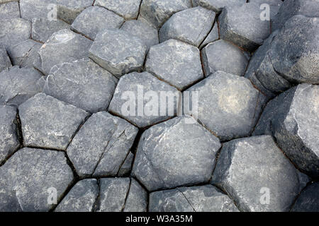 Die Oberseiten der Schwarzen sechseckigen Basaltsäulen Verriegelung auf Causeway Coastal Weg des Riesen, County Antrim, Nordirland, Großbritannien. Stockfoto