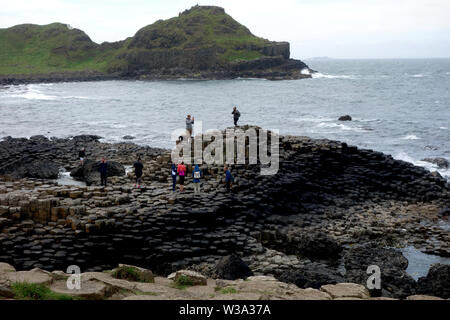 Besucher auf der Oberseite des Schwarzen sechseckigen Basaltsäulen Verriegelung auf Causeway Coastal Weg des Riesen, County Antrim, Nordirland, Großbritannien. Stockfoto