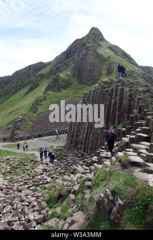 Besucher auf der Oberseite des Schwarzen sechseckigen Basaltsäulen Verriegelung auf Causeway Coastal Weg des Riesen, County Antrim, Nordirland, Großbritannien. Stockfoto