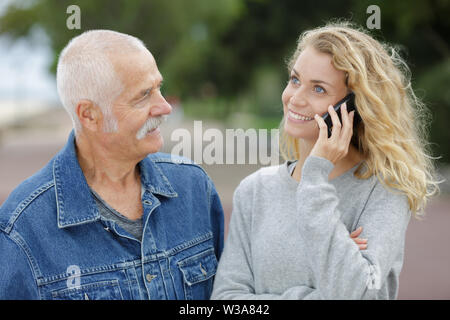 Active Senior, Tochter, die auf dem Telefon Stockfoto