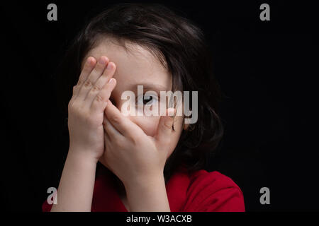 Little Boy spähen durch ein Auge für Gesicht und Augen, mit Hand Stockfoto