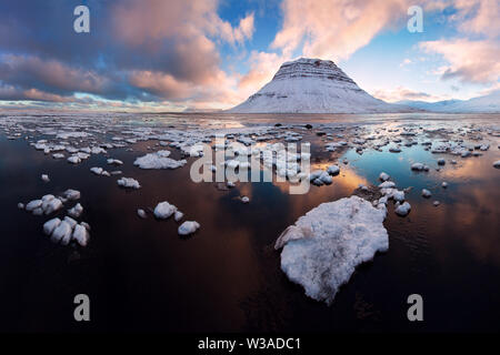 Island snaefellsnes Halbinsel und berühmten Kirkjufell im Winter Sonnenaufgang. Kirkjufell ist ein wunderschön geformter und symmetrischer Berg in Island. Gefroren Stockfoto