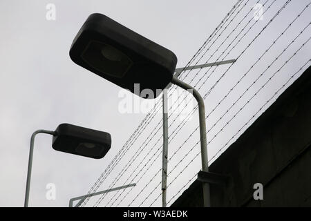 Stacheldraht und Beleuchtung an der Außenwand der Stasi HQ Gebäude komplex, Hohenschonhausen, Berlin, Deutschland. Stockfoto