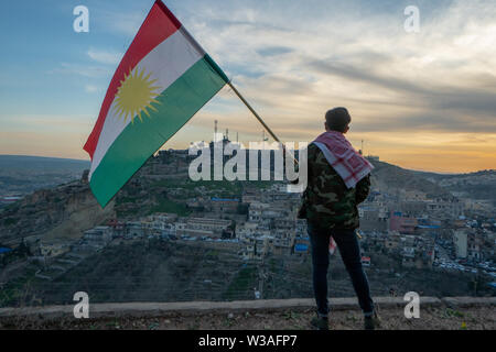 Teenager halten Sie die Flagge Kurdistans im Nordirak bei Sonnenuntergang auf Nowruz 2019 Stockfoto