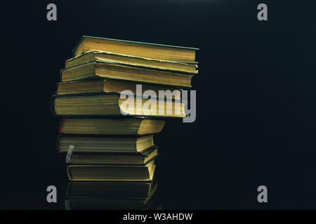 Alte Bücher auf einem Glastisch schwarzen Hintergrund. Stockfoto