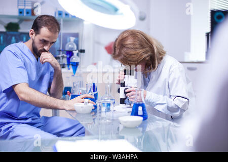 Wissenschaftlerin durch ein Mikroskop im Labor. Junge Ingenieur Betrieb einer biologischen Probe. Stockfoto