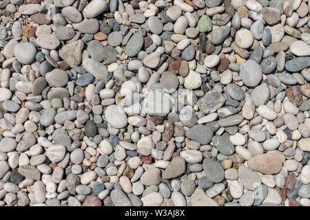 Die Textur der Kieselstrand entfernt. Hintergrund Der kleine Kieselsteine am Strand. Runden Kieseln Stockfoto