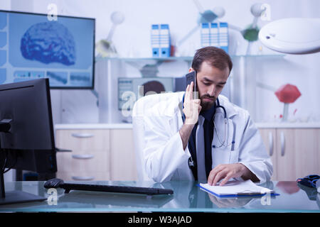 Männlicher Arzt ein Gespräch mit einem seiner Patienten aus dem Krankenhaus. Stattliche Arzt in Uniform. Stockfoto