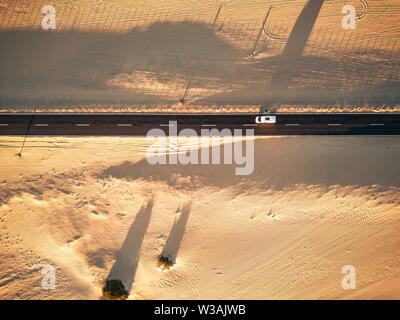 Luftaufnahme von Schwarzen gerade Asphalt mit Sand und wüste auf beiden Seiten rund um das Auto in der Mitte reisen - Begriff der Wanderlust für exotische Stockfoto