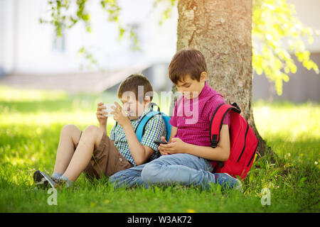 Kinder mit Rucksäcken stehen im Park in der Nähe von Schule Stockfoto