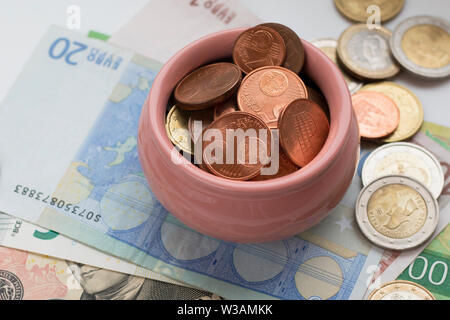 Schale mit Münzen zu den Banknoten Hintergrund. Schatz Konzept, Symbol für Wohlstand und Fülle. Selektiver Fokus Stockfoto