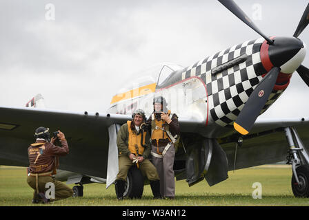 Re-enactors von Engeln auf unsere Flügel, ein Zweiter Weltkrieg Re-enactment Group, posieren für ein Foto von TF-51 D Mustang "Maria" Während der Flying Legends Airshow am IWM Duxford. Stockfoto