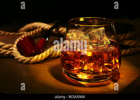 Glas mit Whiskey, Eiswürfel und Rauchen auf Holz- Hintergrund. Stockfoto