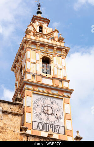 Kirchturm von Carrizo de la Ribera in Valencia, mit gelben, orangen und weißen Quadraten dekoriert, mit der Uhr- und Glockenturm auf einem klaren blauen Himmel Stockfoto