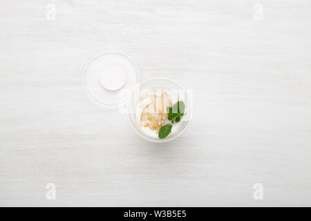 Joghurt birne Schichten und Minze und Pinienkernen liegen in einem Lunch Box auf einem weißen Tisch mit Pinienkernen und Birne Schichten, zerstreut werden. Gesunde Ernährung Konzept Stockfoto