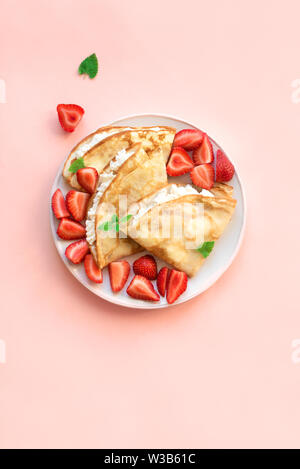 Crepes mit ricotta Käse und frische Erdbeeren auf rosa Hintergrund, Ansicht von oben, kopieren. Köstliche Crêpes, dünne Pfannkuchen. Stockfoto