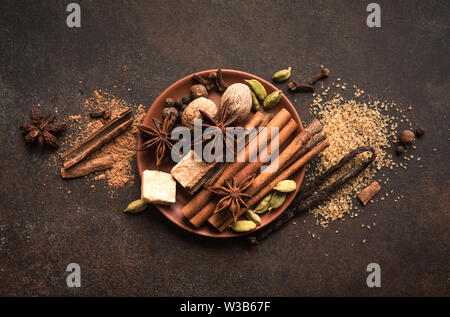 Winter, Gewürzen und braunem Zucker auf dunklen rustikalen Hintergrund, Ansicht von oben, kopieren. Glühwein oder Weihnachten saisonale Backzutaten-Aroma, Gewürze. Stockfoto