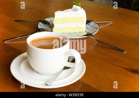 Tasse Kaffee und Stück Kuchen auf hölzernen Tisch im Café. Stockfoto