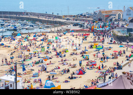 Lyme Regis, Dorset, Großbritannien. 14. Juli 2019. UK Wetter: Massen von strandgängern Herde zu der Strand im Badeort von Lyme Regis zu genießen glühend heiße Wochenende Sonnenschein. Credit: Celia McMahon/Alamy Leben Nachrichten. Stockfoto