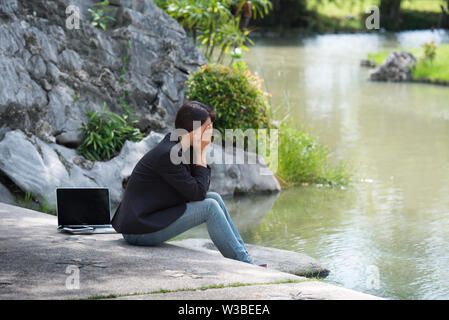 Serious Business Frau hart arbeiten mit ernsten Problem in einem öffentlichen Park. Arbeiten am Laptop im Freien. Zugeschnittenes Bild der weiblichen Arbeiten am Laptop, während si Stockfoto