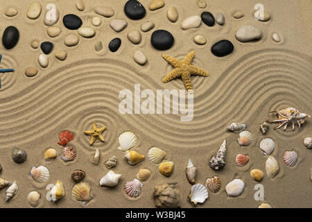 Steine, Muscheln und Sterne liegen auf den Wellenlinien von Sand. Ansicht von oben Stockfoto