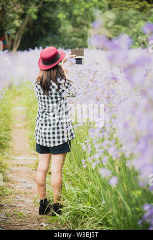 Junge schöne asiatische Frau die Foto im Freien mit DSLR Digitalkamera. Junge fröhliche weibliche Touristen Spaß im Coffee Shop. Lifestyle portrai Stockfoto