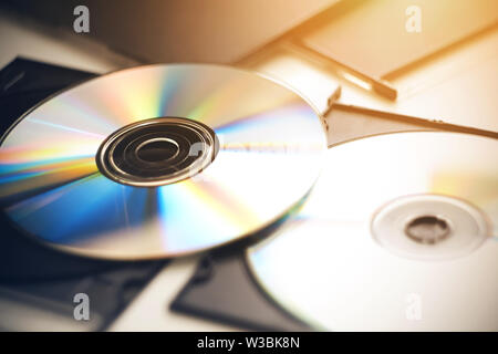 Mehrere CDs liegen auf einem weißen Tisch in ihren schwarzen Kästen, die durch Sonnenlicht beleuchtet und schimmert in verschiedenen Farben. Stockfoto