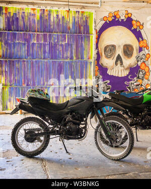 Garage mit einem Motorrad auf eine mehrfarbige Wand und Farbe eines Schädels Stockfoto
