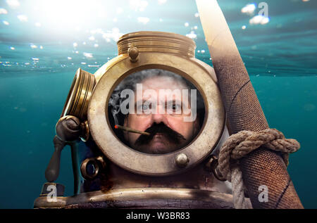 Porträt des Menschen in alten Taucheranzug und Helm unter Wasser. Lustige Taucher in retro Ausrüstung raucht im Helm. Stockfoto