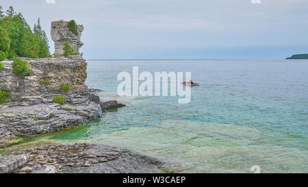 Lone kayaker paddeln Vergangenheit eines der geologische Formation auf Blumentopf Insel Georgian Bay Ontario. Stockfoto