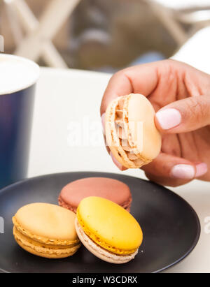 Verschiedene süße frische französische Macarons in Mädchen Hand. Stockfoto