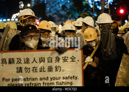 Die demonstranten stehen gegen Polizisten während eines Protestes im Distrikt Shatin, Hong Kong. Die meisten von ihnen tragen Bau Helm und hausgemachte Schild. Tausende von pro Demokratie Demonstranten auf die Strasse wieder einmal in eine neue Welle von Demonstrationen gegen die Regierung, die durch die Auslieferung Rechnung, die die Regierung von Hongkong, wurde im Juni 2019 zu drücken ausgelöst werden. Nach Angaben der Polizei mindestens 30 Festnahmen, als die Demonstranten mit der Polizei am Abend stießen gemacht hat. Stockfoto