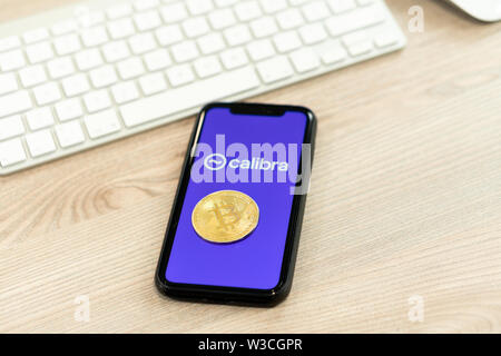 12 Juli 2019, Ljubljana Slowenien - Smartphone mit Calibra Logo neben Bitcoin Münze. Facebook Neue globale cryptocurrency für Transaktionen Stockfoto