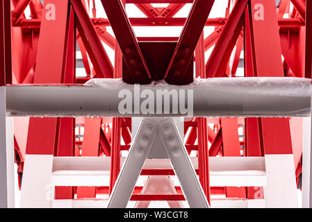 Pylon, roter und weißer Turm aus lackiertem Stahl. Die Fragmente mit den Details der Konstruktion, verbindet, Nieten. Stockfoto