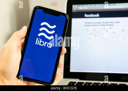 12 Juli 2019, Ljubljana Slowenien - Hand Smartphone mit Waage Logo neben Facebook webseite. Facebook Neue globale cryptocurrency Stockfoto