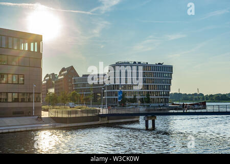 Blick auf den Hafen der Stadt Rostock mit modernen Gebäuden - Sonnenuntergang Himmel mit hellen Sonne Stockfoto
