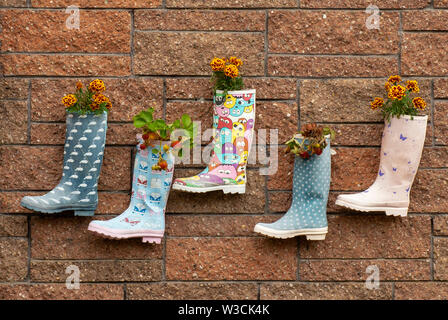 Ist lustig, Kinder Kid's Wellington welly boots Blumentöpfe mit Erdbeeren und Blumen gepflanzt, die Mauer in irischen Kindergarten. Stockfoto