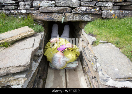 Eine Frau in das Grab der Eagles, Grabhügel, chambered Cairn auf South Ronaldsay, Orkney, Schottland, Großbritannien. Stockfoto