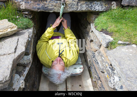 Eine Frau in das Grab der Eagles, Grabhügel, chambered Cairn auf South Ronaldsay, Orkney, Schottland, Großbritannien. Stockfoto