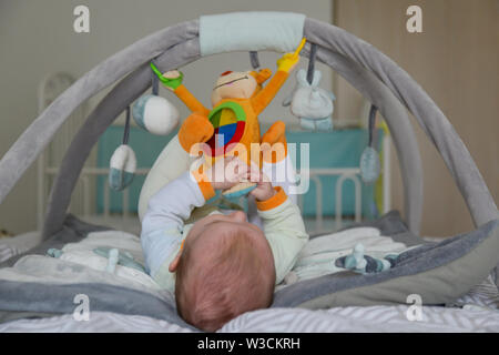 Baby Junge spielt mit hängenden Spielzeug auf die Entwicklung von Mat Stockfoto