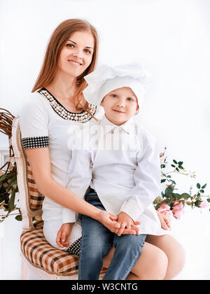 Portrait von Mama und ihrem kleinen Sohn in einem Küchenchef Anzug sitzen zusammen Stockfoto