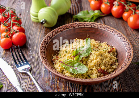 Couscous in Schüssel mit Olivenöl und getrockneten Tomaten auf Holzuntergrund, orientalische Küche, horizontale Foto, in der Nähe Stockfoto