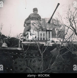 Deutscher Soldat in schwerer Winterkleidung auf einem mobilen Leichtflakfahrzeug an der Russischen Front 1943 . Ein privates Schwarzweiß-Foto des Zweiten Weltkriegs Stockfoto